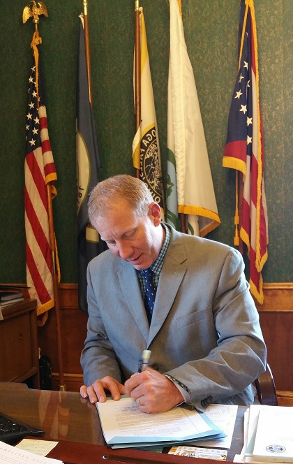 Mayor Walters signs ordinance allowing spouses to be buried with their veteran partners at Oakwood Cemetery. 